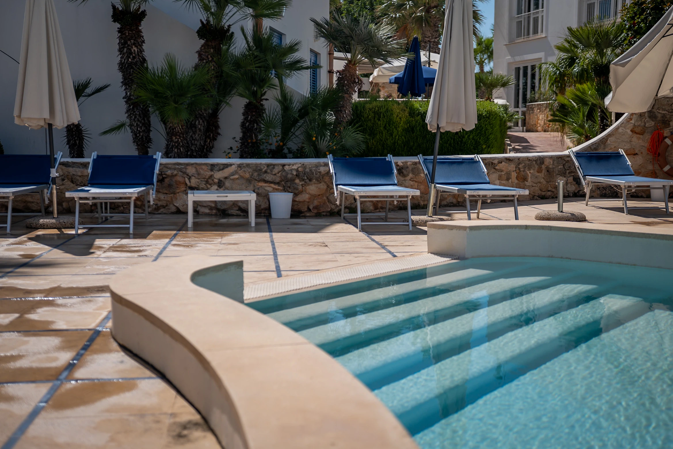 Gradini arrotondati della piscina e lettini sul solarium