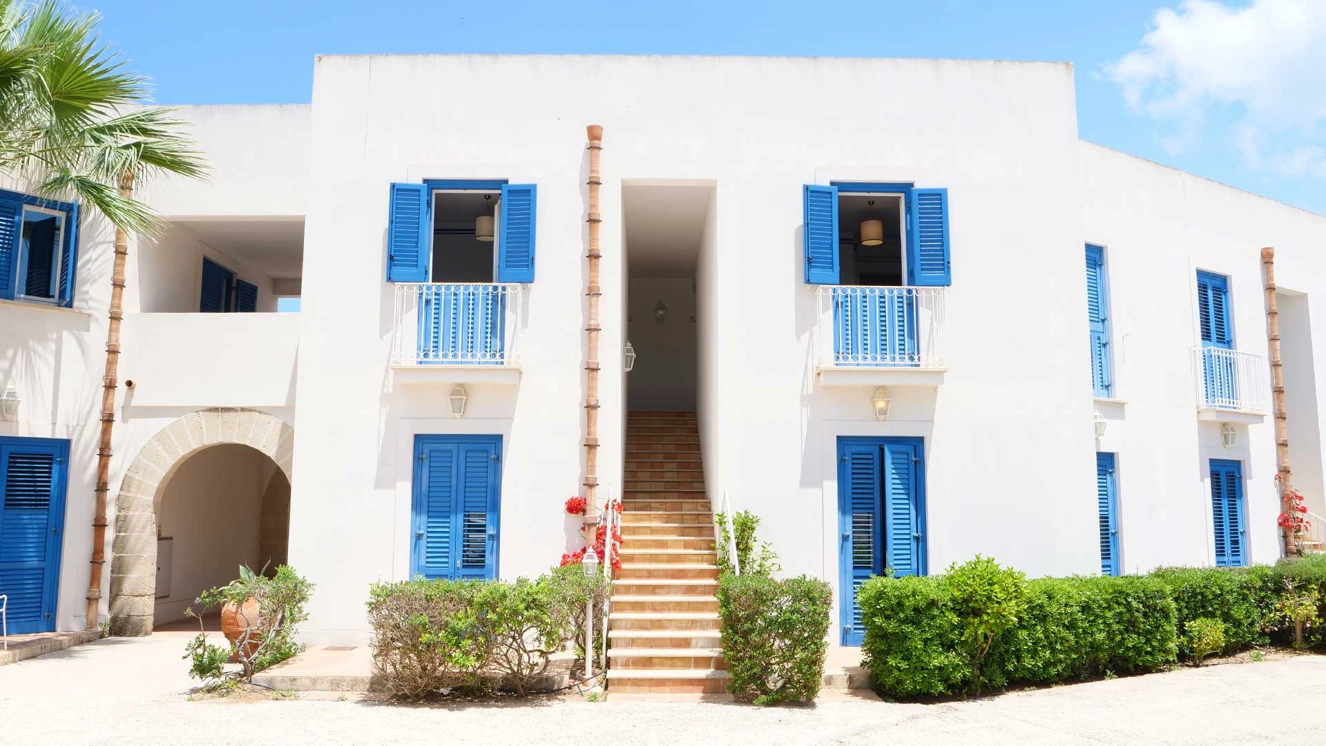 Facciata bianca con balconi blu del resort Cala La Luna